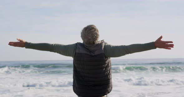 Caucasian woman enjoying free time by sea on sunny day standing with arms wide