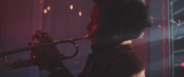 Professional trumpeter playing in a room with smoke and red neon light