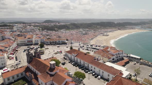 Sítio da Nazaré overlooking amazing beach and resort town, Portugal. Aerial forward view