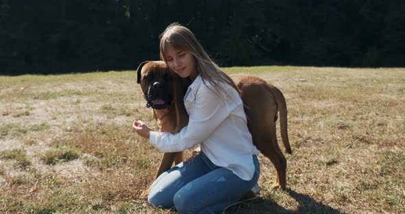 Happy Young Female Cheerfully Playing Sitting with Dog in the Lawn. Love and Friendship with