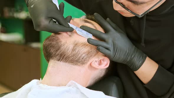 Skilled Barber Holds Special Silver Blade and Trims Beard