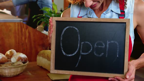 Female staff holding a open sign slate in supermarket