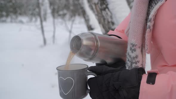 Woman Pouring Hot Tea in a Mug in Winter Day