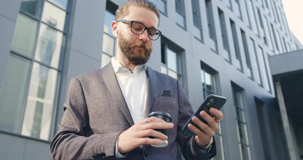 Man in Business Suit which Drinking Coffee and Listening Music Near Office Building