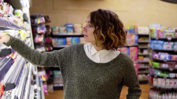 Food Health Concept Woman in a Supermarket Standing in Front of the Freezer Shelfs and Choose Buying