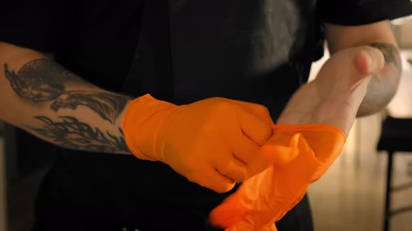 Tattoo Artist Wears Sterile Orange Gloves, Close Up