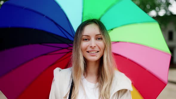 Caucasian Woman Spinning Multicolored Umbrella and Smiling