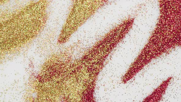 Blowing Gold and Red Glitter on White Background Gloss Golden Powder Closeup