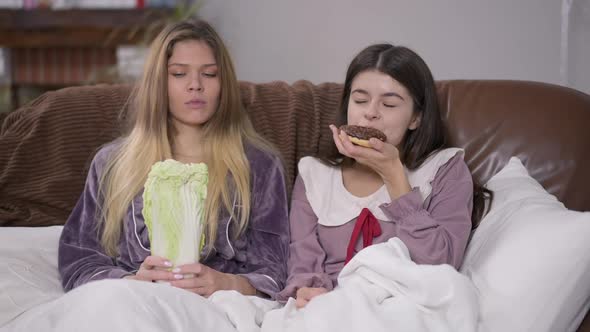 Portrait of Happy Woman Eating Sweet Doughnut As Friend Chewing Cabbage