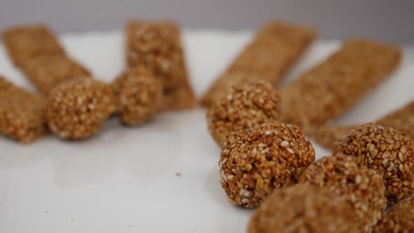 Micro shot of dropping sesame seeds ladoo over a plate