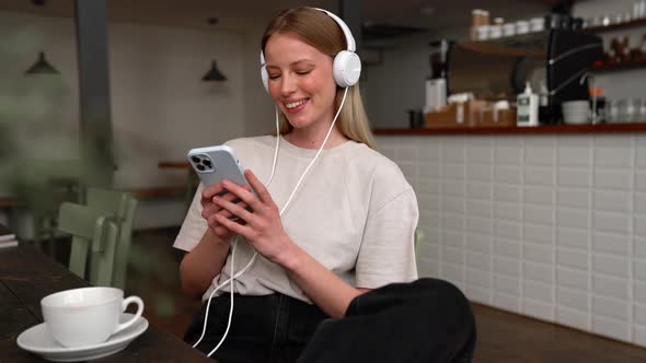 Pleased blonde woman listening music in headphones