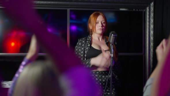 Joyful Talented Plussize Redhead Woman Clapping and Singing with Microphone on Stage As Crowd