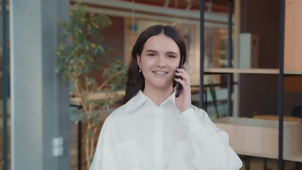 Portrait of a Young Girl Yak in the Office Talking on the Phone Laughing and Wondering at the Camera