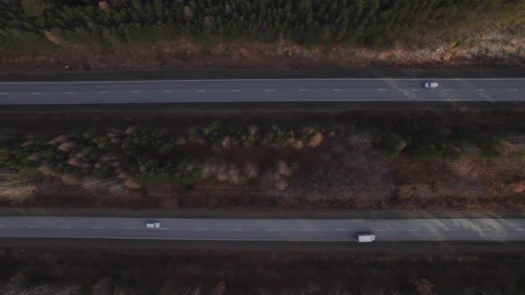 Traffic cars on multiple lane highway road between deep forest