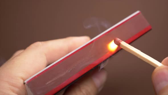 Slow motion shot of male hand igniting match on matchbox.Close up footage.