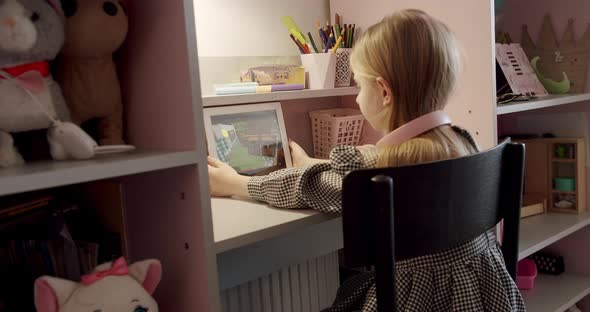 Little Girl in the Children's Room with Pink Headphones Using Digital Tablet