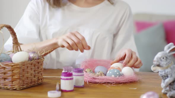 Female Hands Putting Easter Eggs into Basket