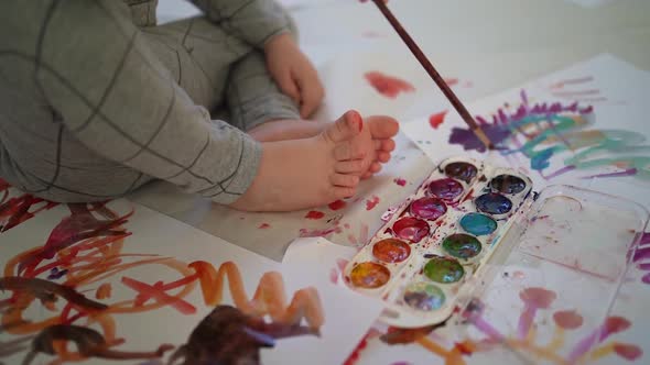 C0079little boy of two years old draws with paints sitting on the floor