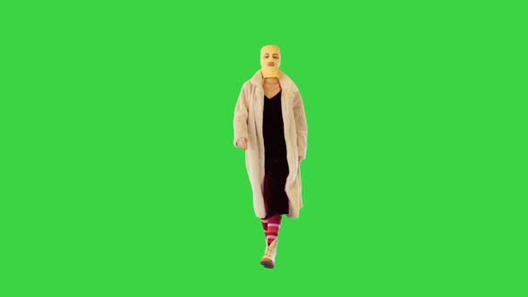 Young Caucasian Girl in Balaclava Walks Confidently Making Energetic Hand Gestures on a Green Screen