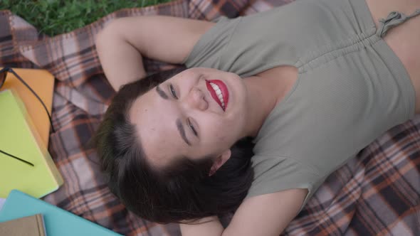 Top View Portrait of Happy Caucasian Little Woman Looking at Camera Smiling Lying on Blanket