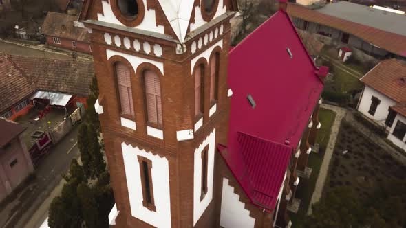 Aerial Drone Zoom out and Fly over Of from a door of red roofed church in a small city village in ro