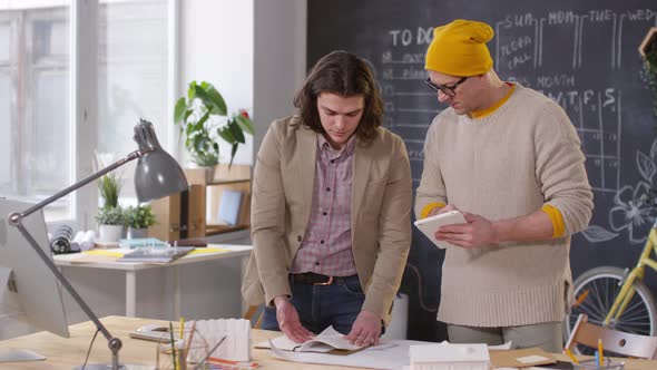 Designer Discussing Project with Colleague in Office