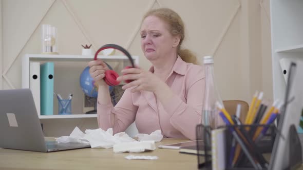 Mad Caucasian Woman Crying, Putting on Headphones and Start Dancing To Music in Earphones. Portrait