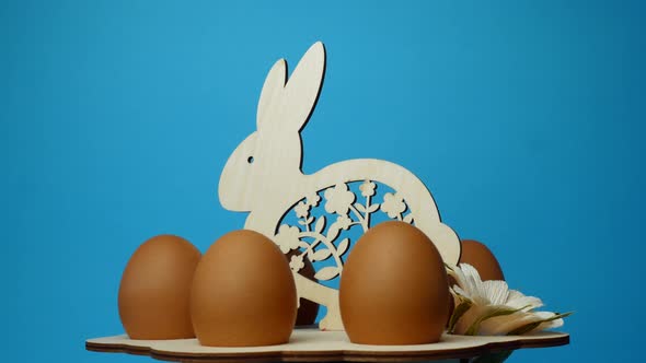 Rotation of eggs in an Easter stand made of wood on a blue background. Easter concept.