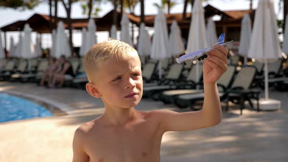 Closeup of a Little Boy Playing with a Toy Airplane Near the Pool in the Hotel