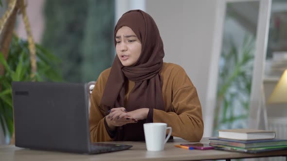 Portrait of Confident Professional Middle Eastern Young Woman in Hijab Talking at Laptop Video Chat