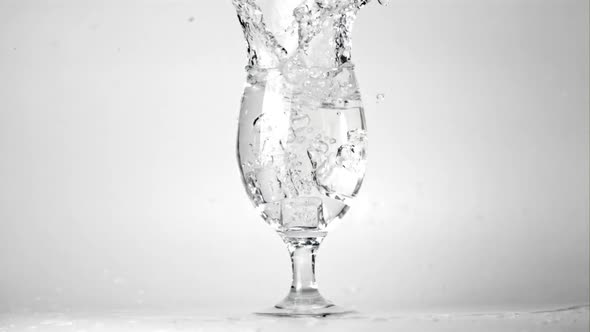 Super Slow Motion Ice Falls Into a Glass of Water with Spray