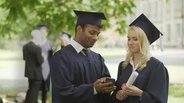 Young People in Graduate Uniform Looking at Phone Screen, Having Discussion, Job