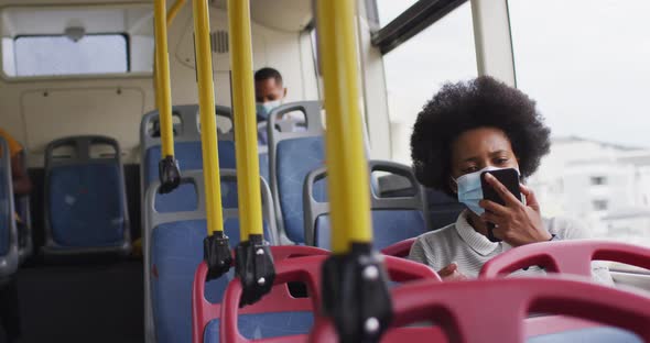 African american man and woman with face masks sitting in bus