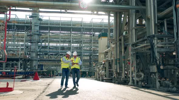 Pipelines of the Oilprocessing Plant with Two Inspectors Passing By