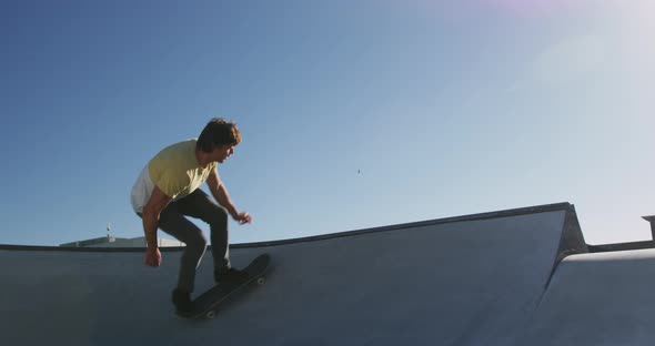 Caucasian man riding and jumping on skateboard on sunny day