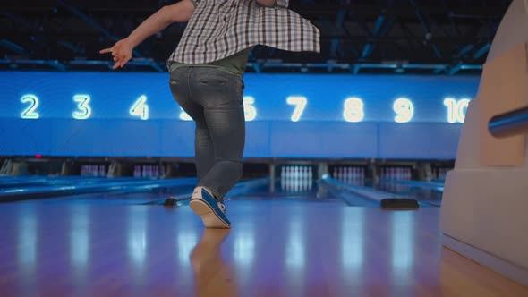 The Camera Follows One Caucasian Man Throwing a Bowling Ball on the Playing Track and Jumping