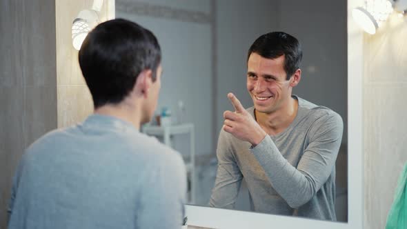 Man Inspires Himself in Front of a Mirror