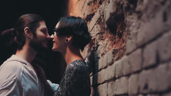 Young Gothic Hipster Couple Admiring Each Other on the Background of Brick Wall