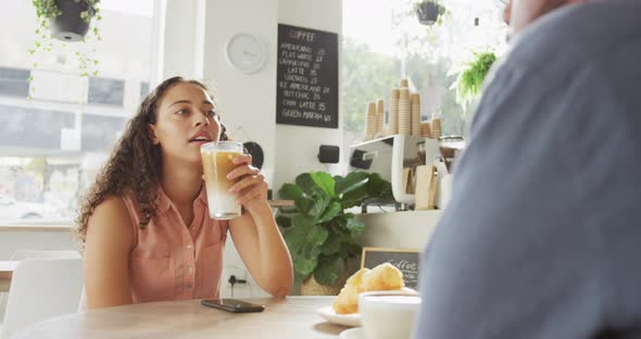 Happy diverse couple spending time together at cafe, drinking coffee and talking