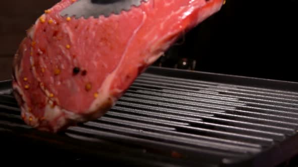 Cook Puts Steak Using Tongs on the Grill Grate