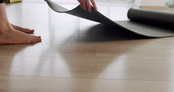 Closeup Attractive Woman Unfolds a Rug for Practicing Yoga in the Studio