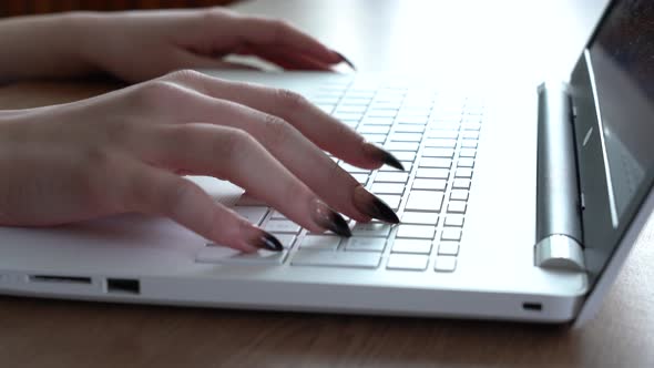 Female Hands of a Woman Typing on a Laptop Keyboard While Sitting at Her Desk