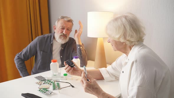 Senior Couple Using Glucometer For Blood Sugar Monitoring