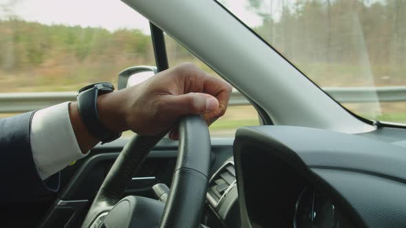 Hand of Black Male Driver Holding Steering Wheel During Driving