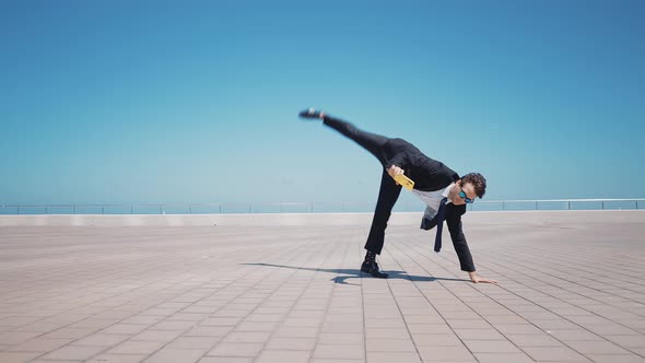 Flexible and cool businessman doing acrobatic tricks outdoor