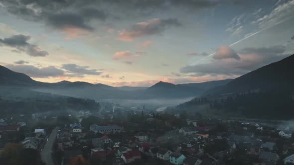 Houses in White Morning Mist Against Hills Hiding Sun