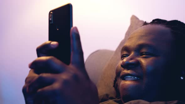 Man Relaxing in the Couch and Browsing Dating Site on His Smartphone