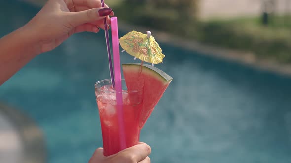 Woman Holds Glass and Puts Pink and Purple Straws Inside