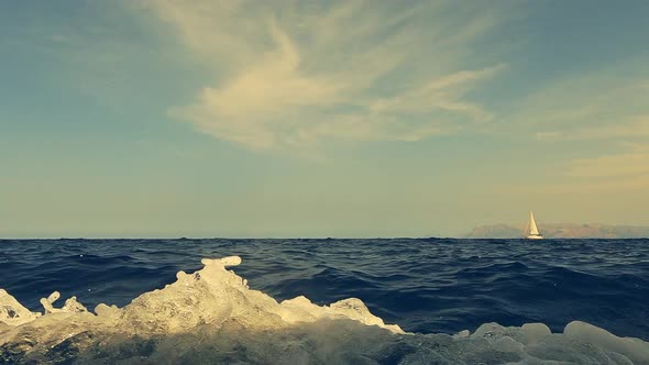 Low-angle water surface view of sailboat navigating on seawater as seen from another cruising vessel