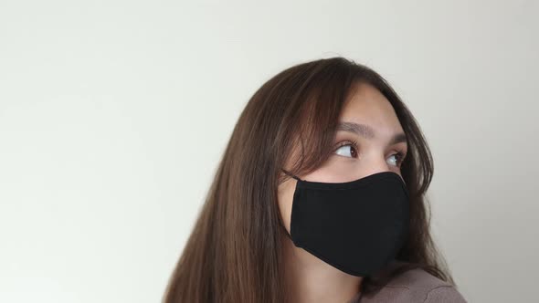 Portrait of Thinking Young Brunette Female in Black Protective Medical Mask